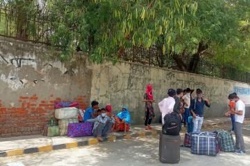 Migrant workers in India sitting on the sidewalk 