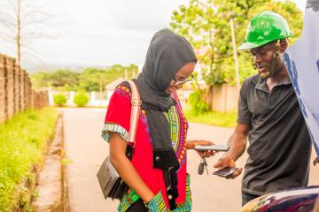 A woman pays mechanic through a mobile phone transfer