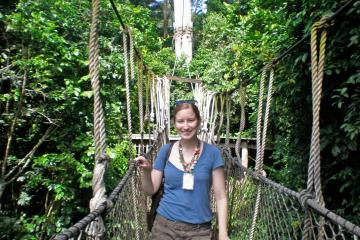 Caitlin Tulloch stands alone on a dangling bridge in a forest