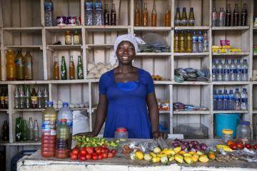 Woman in Ghana stands in front of her roadside restaurant preparing food