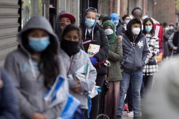 People wearing masks stand in a line. 