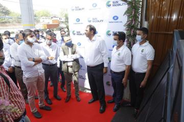 Jasmine Shah stands among a crowd of people looking at an electric vehicle battery swapping facility.