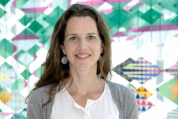 Kelly Bidwell stands in front of a colorful pattern backdrop