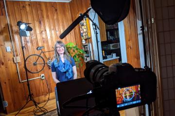 Laura Feeney sits on a stool in front of a camera