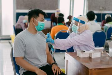 A man sitting in a chair receives a Covid-19 vaccine to the arm