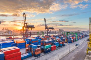 A port in Morocco with several shipping contains and cranes at sunrise.