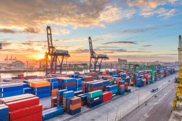 A port in Morocco with several shipping contains and cranes at sunrise.