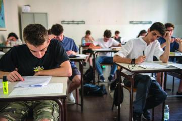 students sit at desks inside a classroom working on an assignment