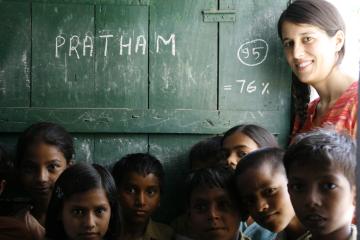 Francisca stands next to a chalkboard behind a group of young children