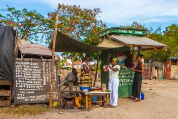 Women prepare food for sale in front of a shop in Kenya.