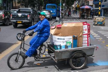 A woman rides a tricycle to collect recyclables, which she negotiated with building administrators, neighbors, and hotel managers 