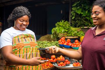 African women in a local market doing a digital transaction. 