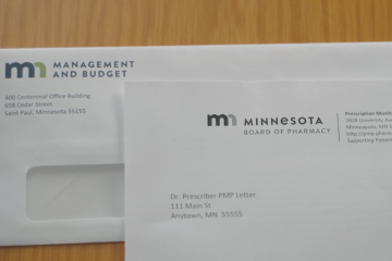 Two envelopes; one with the Minnesota Management and Budget Logo and text "400 Centennial Office Building 658 Cedar Street Saint Paul, Minnesota 55155." The other with the Minnesota Board of Pharmacy Logo and text "Prescription Monit 2828 University Av Minneapolis, MN 5 http://pmp.pharm Supporting Patien. Dr. Prescriber PMP Letter 111 Main St Anvtown. MN 55555" 