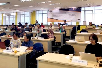 Rows of people in a classroom with laptops.