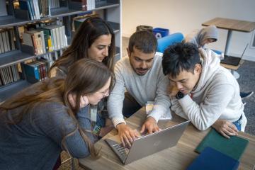 Four students collaborating around a computer