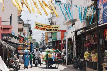 People walking in narrow street with full of food stalls during daytime in India