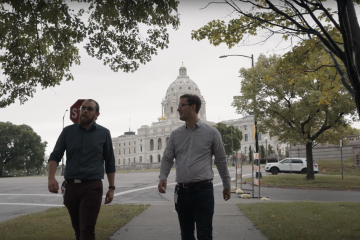 Two people walking in front of a state capitol building