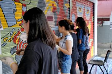 Three young adults paint a mural