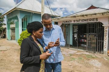 Man and woman standing in front of a store looking at their phones