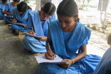 Female students sitting on the ground while working on an assignment