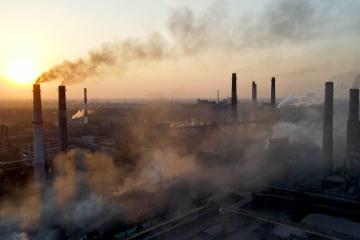 View of a factory at sunset with the smoke billowing from the stacks