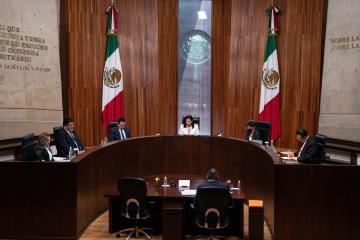 Five people sit around an oval bench in front of another individual in a courtroom in Mexico City