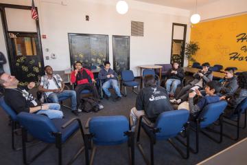Group of students sit in a circle laughing with two adult group leaders