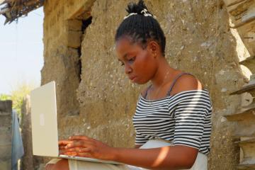 Woman sitting next to a building working at her laptop