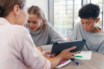 Teacher holds a tablet while a male and female student review 