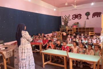 A woman teaches a class of young children in a nursery.