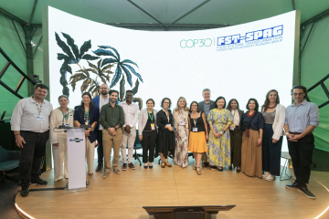 Colleagues stand in a line in front of a projector smiling.