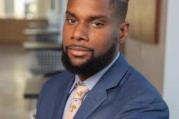 A photo of Damon Jones with a background of the University