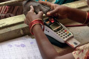 Woman uses a small machine to scan a person's fingerprint