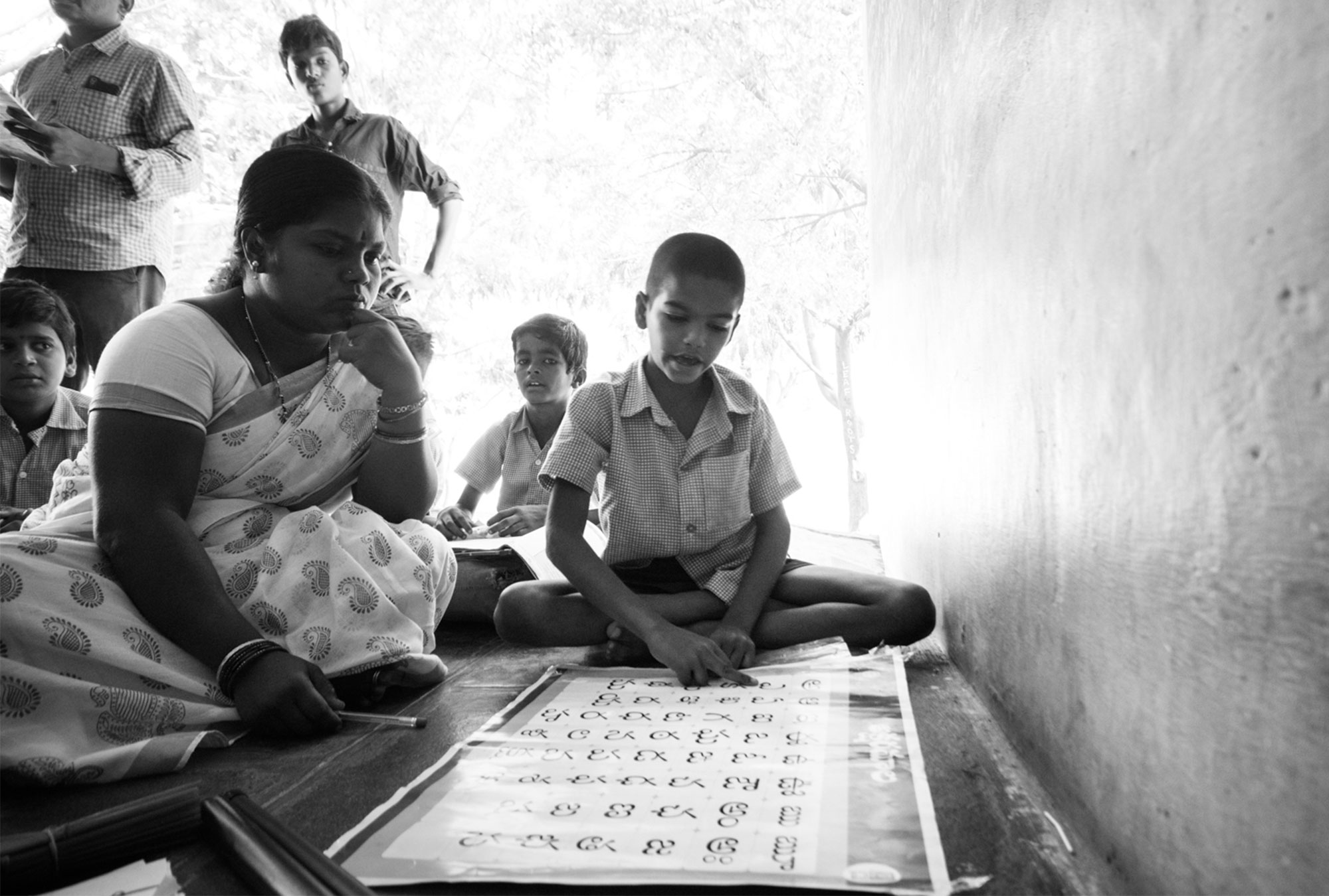 A teacher assists student in reading the alphabet